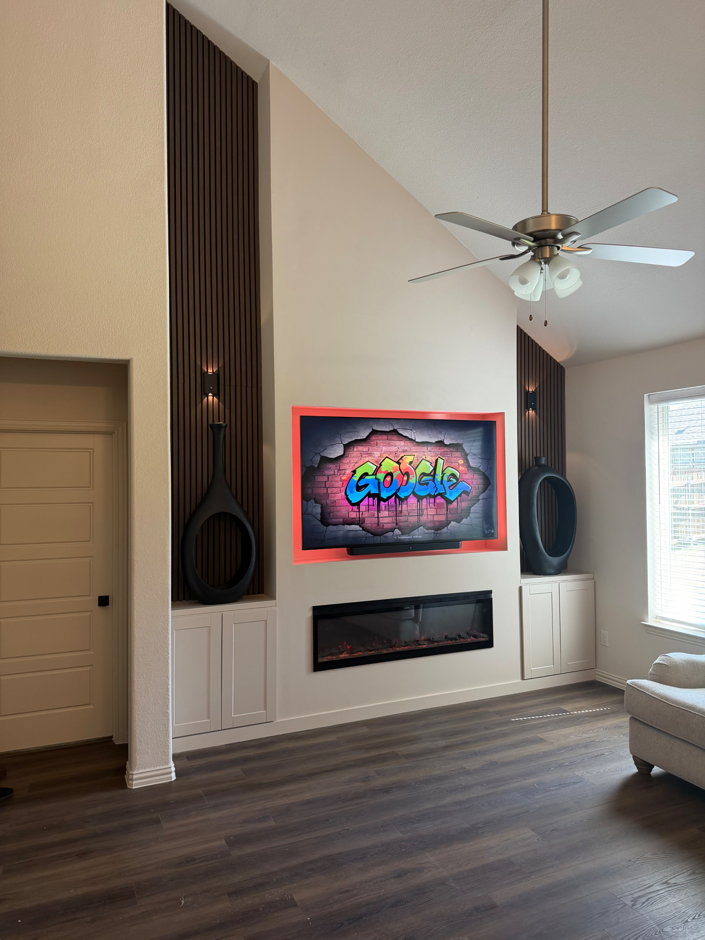 Custom media wall with acoustic slat paneling, backlit television, and linear electric fireplace