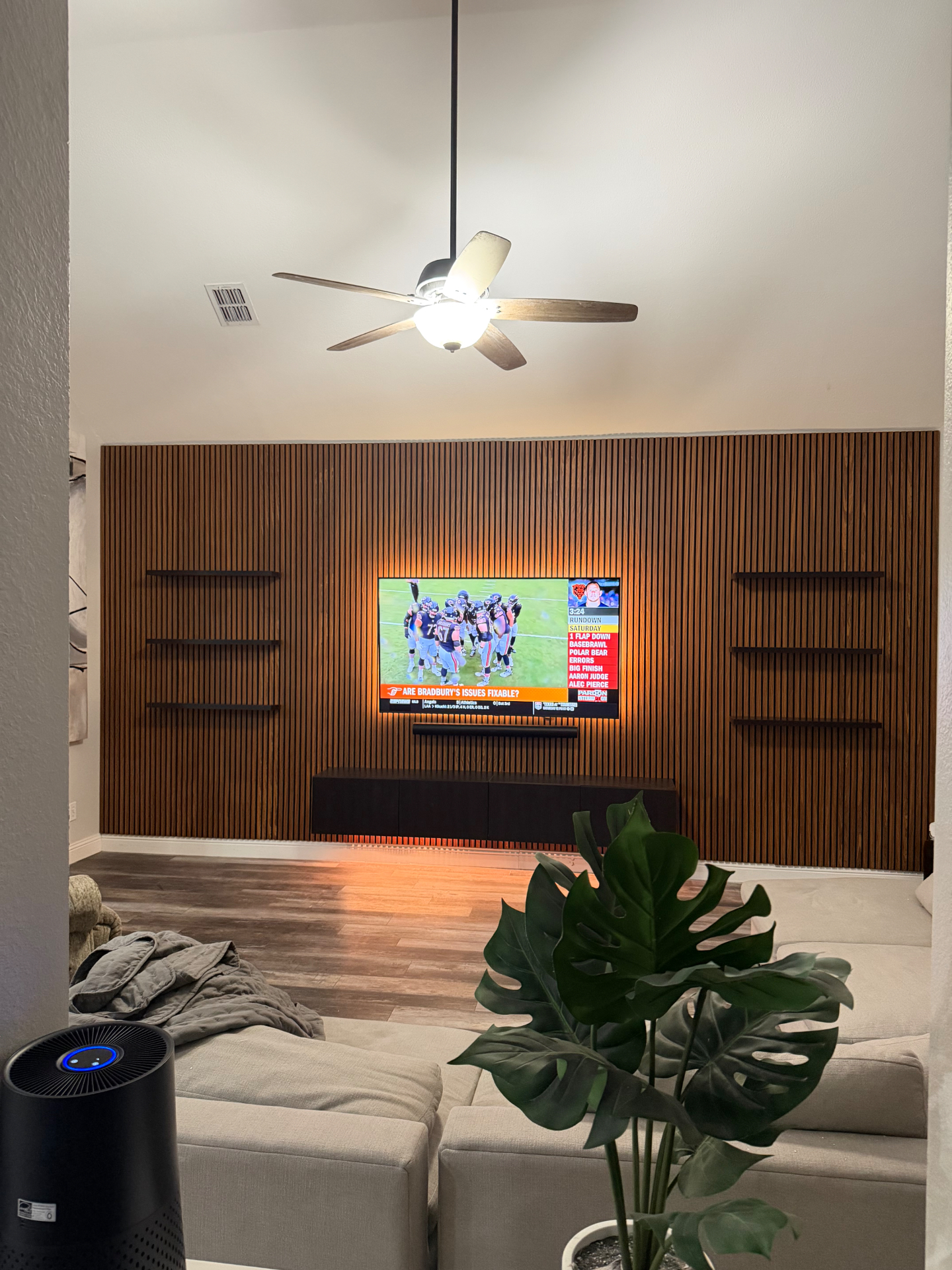 Wood acoustic slat wall with backlit TV and floating shelves